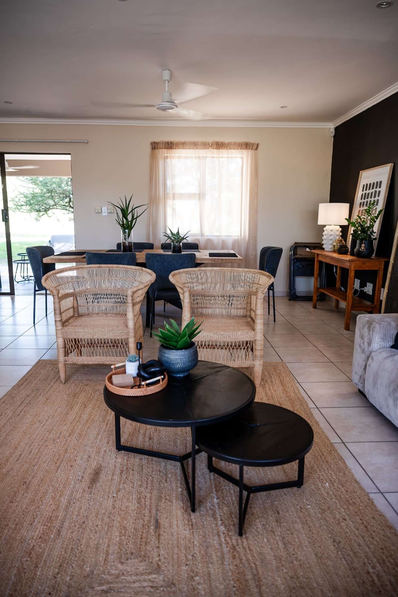 Dining table with wicker chairs, aloe plants and a jute rug in the open-plan living area