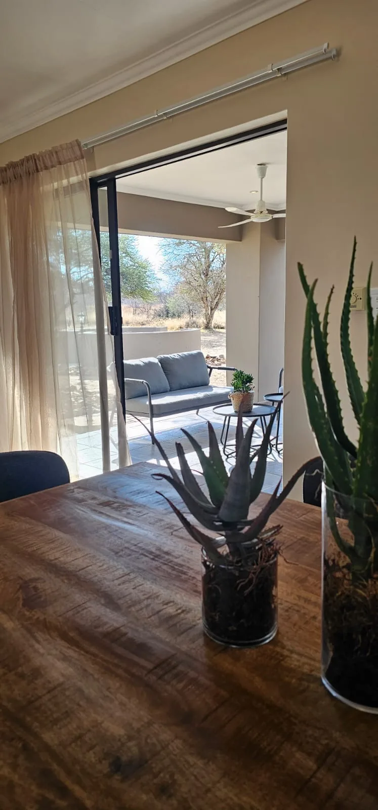 View from the dining table through the open sliding doors to the covered patio and the bush beyond