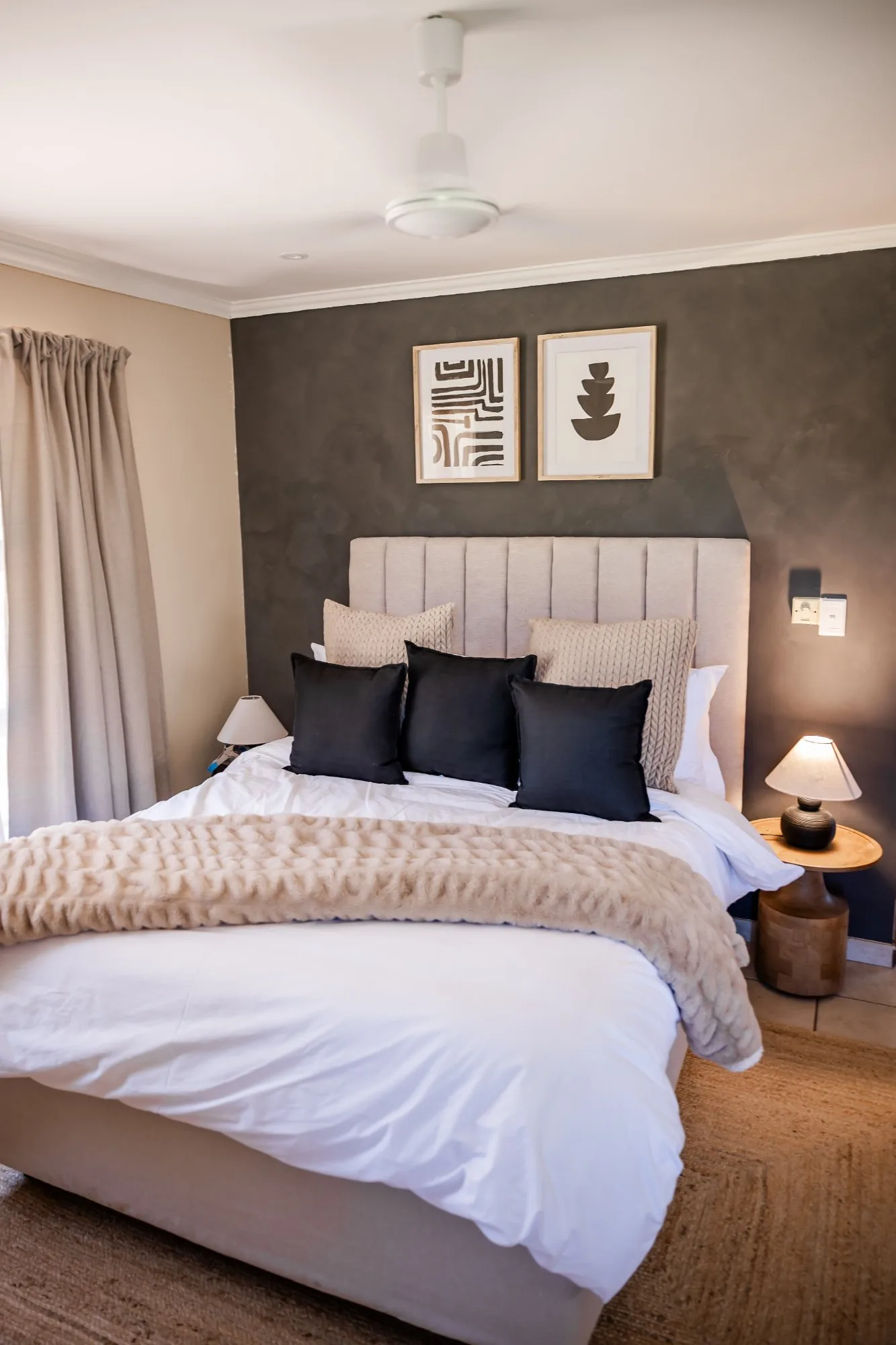 Queen bedroom with a charcoal feature wall, framed abstract art and black scatter cushions