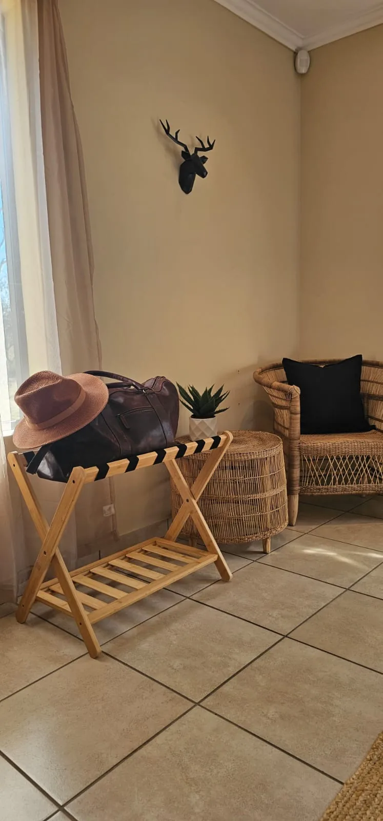 Bedroom corner with a luggage rack, wicker armchair and small side table
