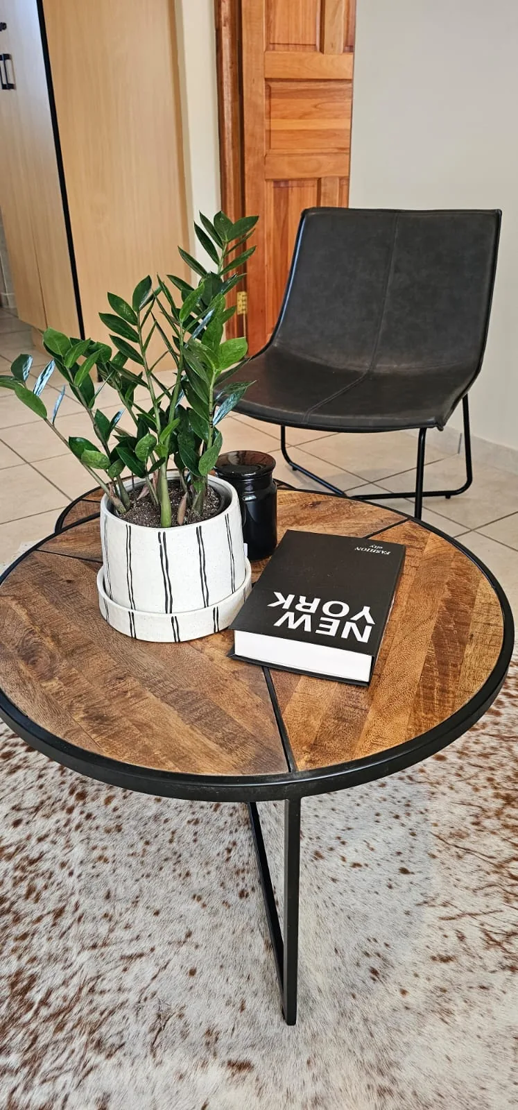 A quiet corner with a leather chair, a round side table, a pot plant and a book