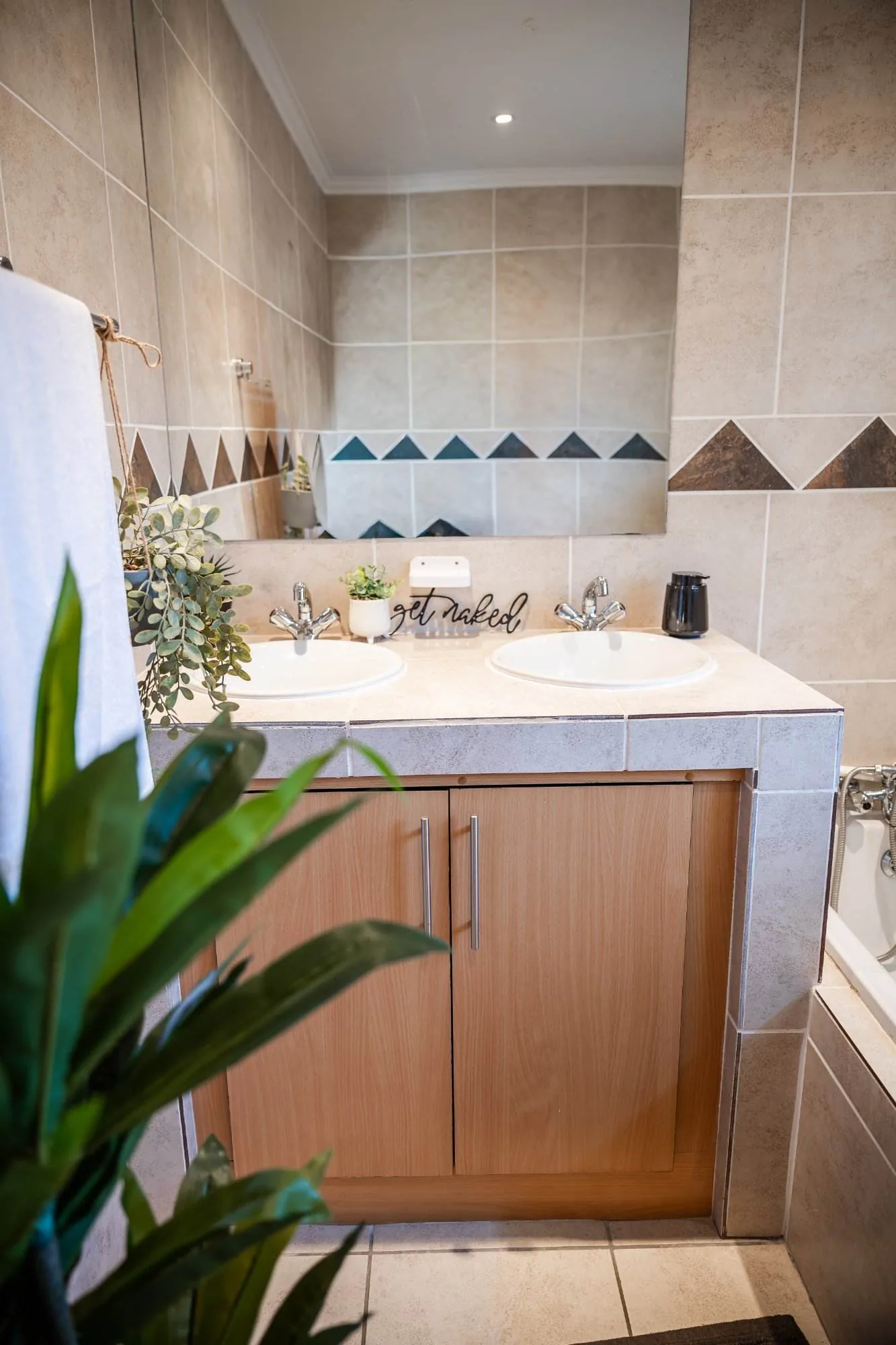Second bathroom with a wooden vanity unit and patterned wall tiles